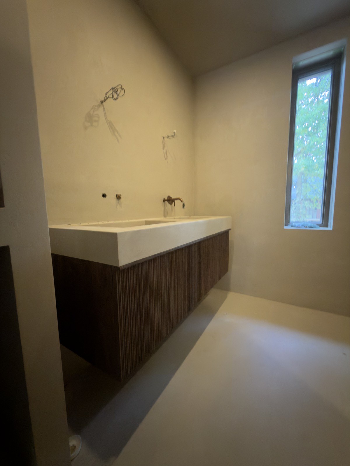Badkamer met wastafel op een donker ribbenfront en een smal raam