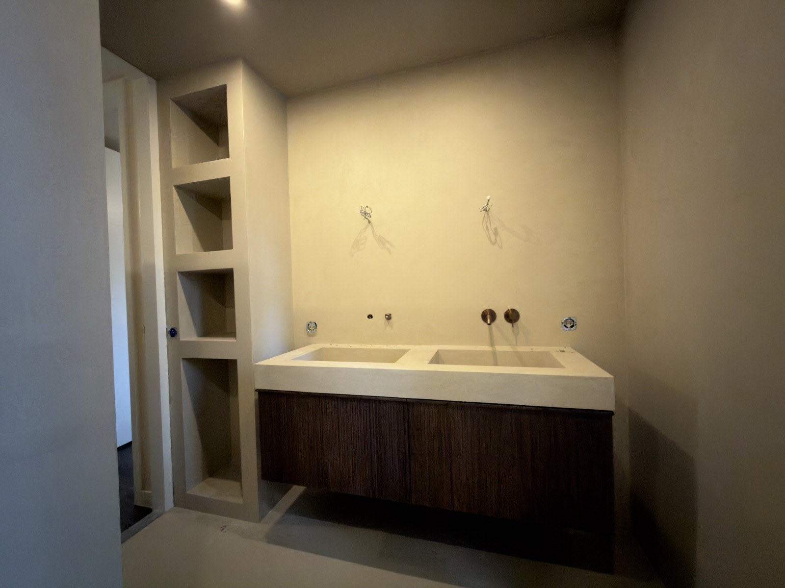 Dubbele wastafel met ingebouwde nissen in een badkamer met microcement