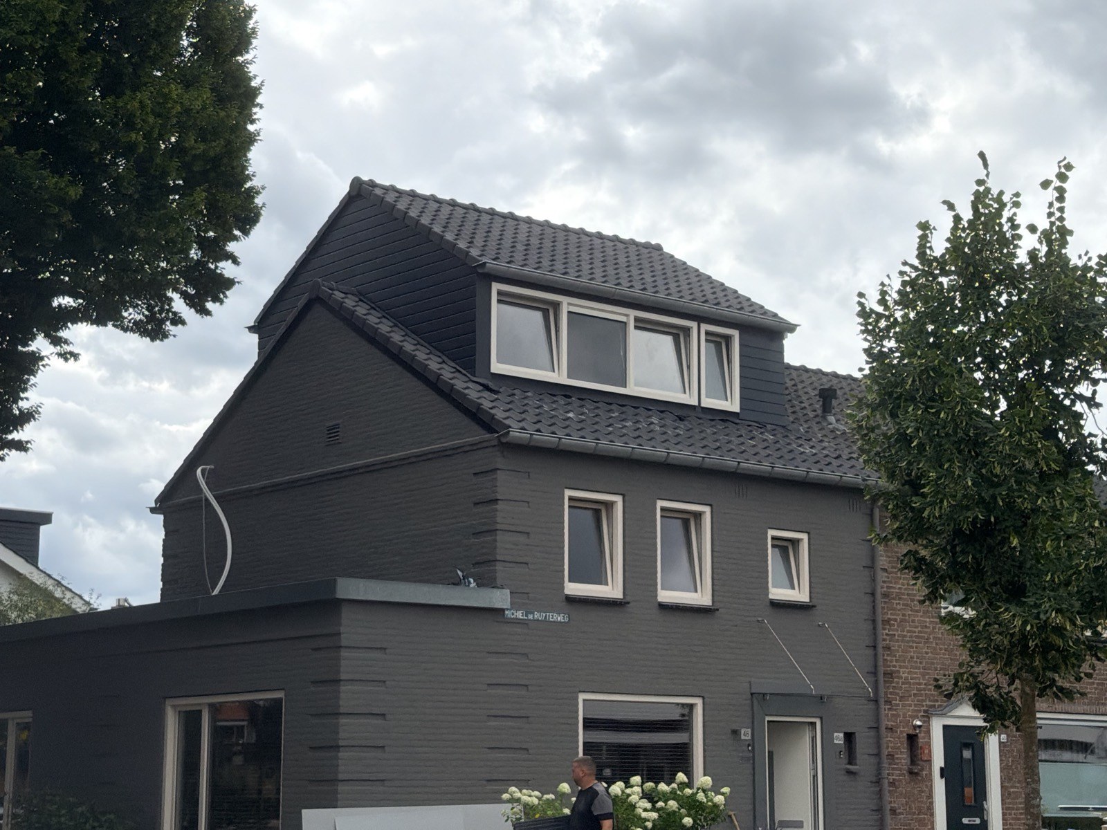 Woning met een nieuwe brede dakkapel en donkere dakpannen