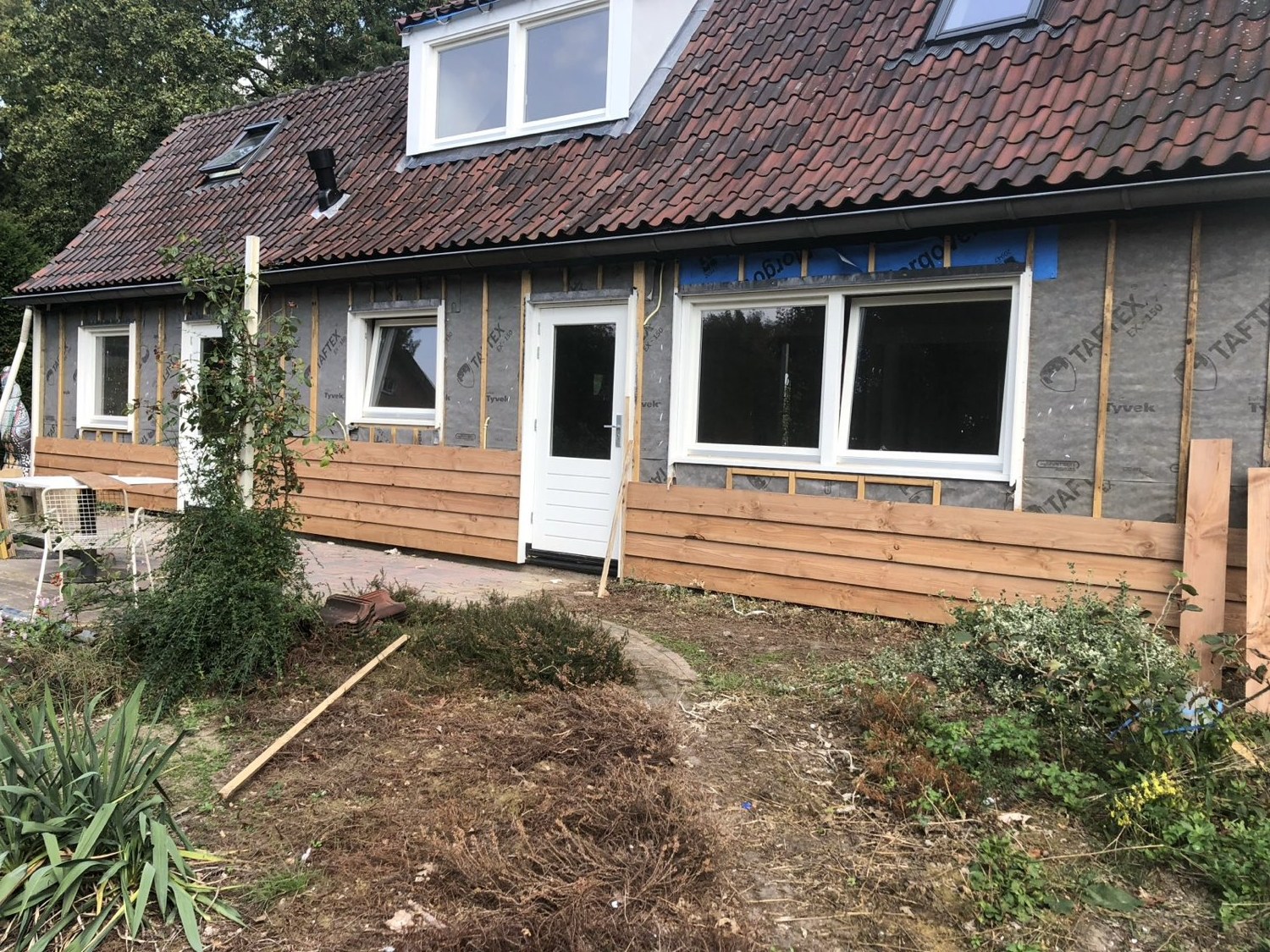 Houten gevelbekleding wordt aangebracht over de isolatie van een woning