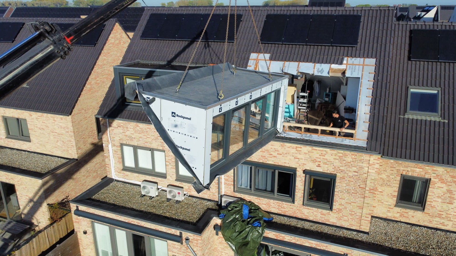 Complete dakkapel hangt aan een kraan boven het dak van een woning