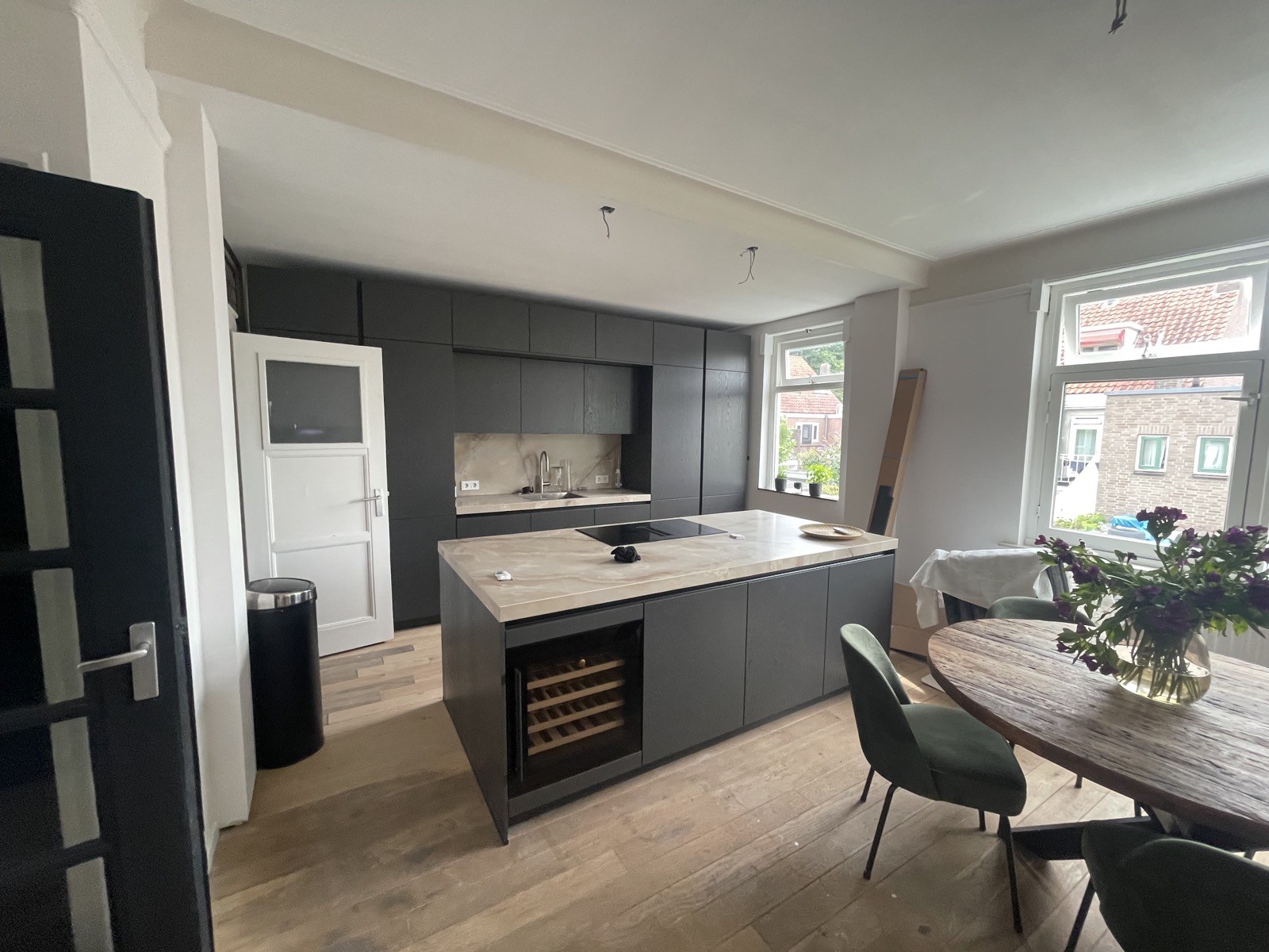 Donkergrijze keuken met wijnklimaatkast na een complete woningrenovatie