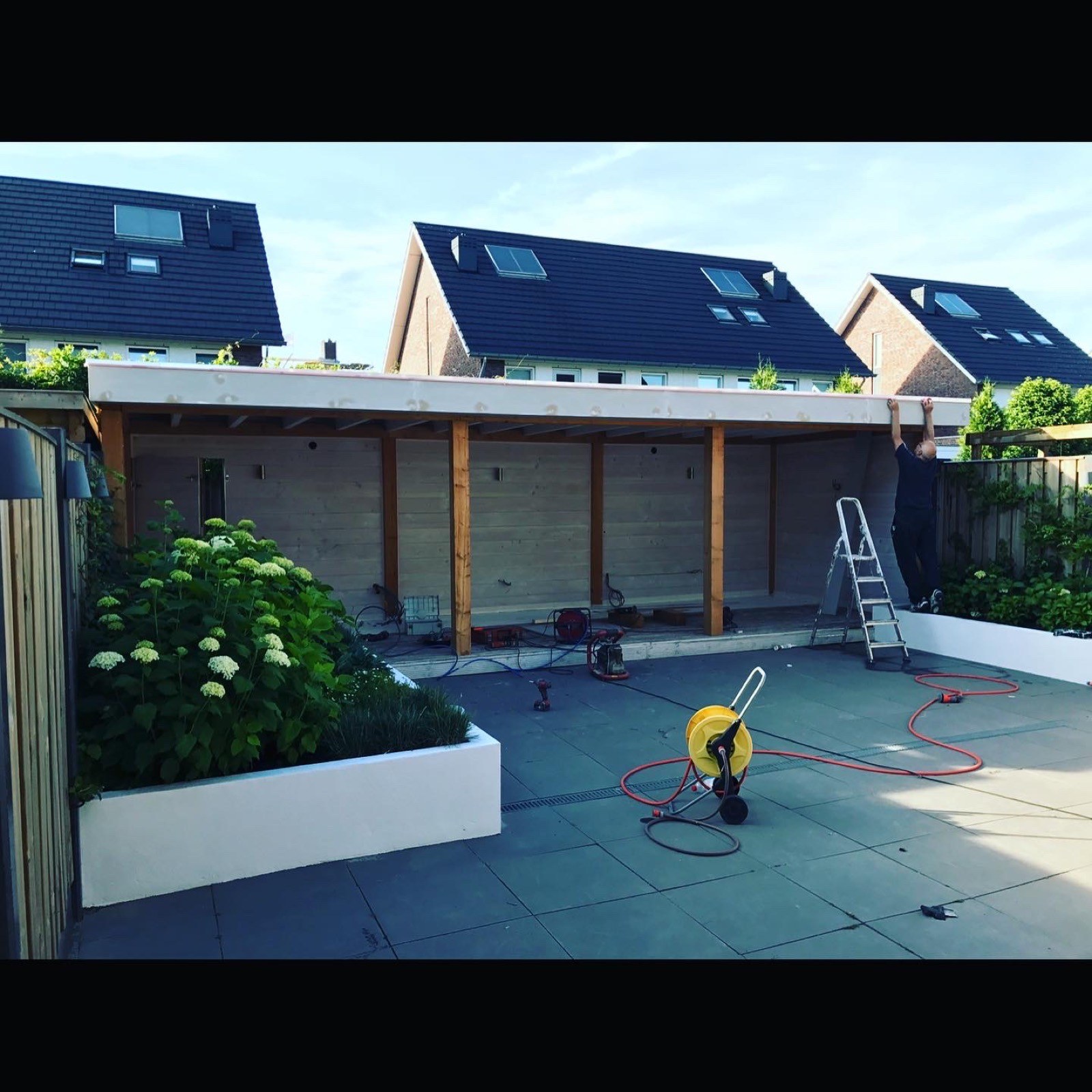 Houten overkapping in aanbouw over de volle breedte van een tuin