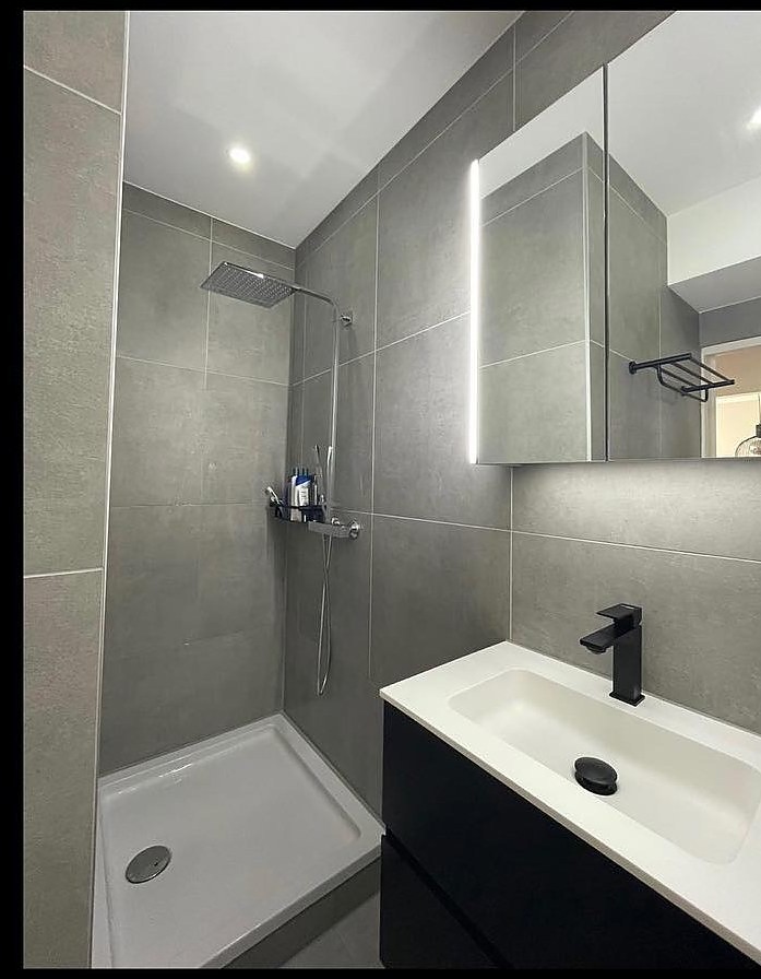 Dezelfde badkamer na de renovatie, met een ruime inloopdouche en spiegelkast