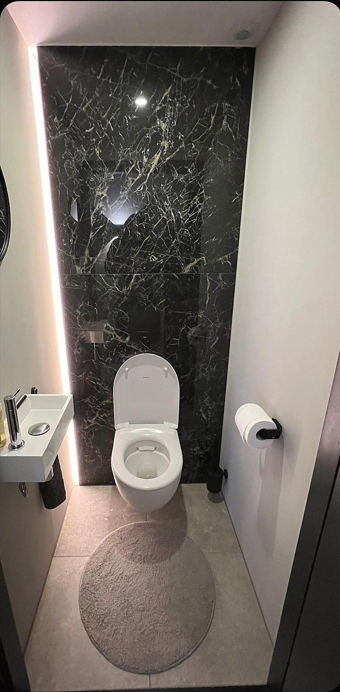 Hetzelfde toilet na de renovatie, met zwart marmer en indirecte verlichting